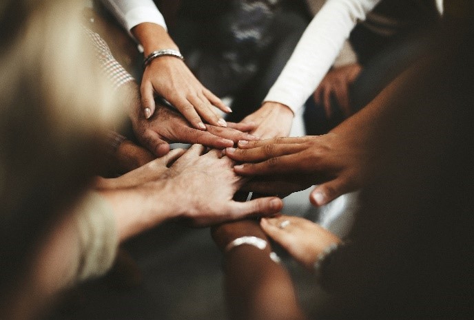 Various hands and arms of people together in a circle that represents inclusion.