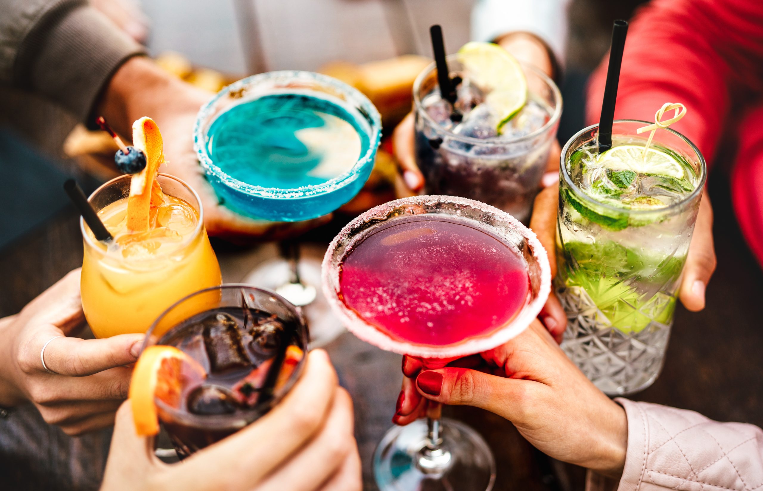 People hands toasting multicolored fancy drinks - Young friends