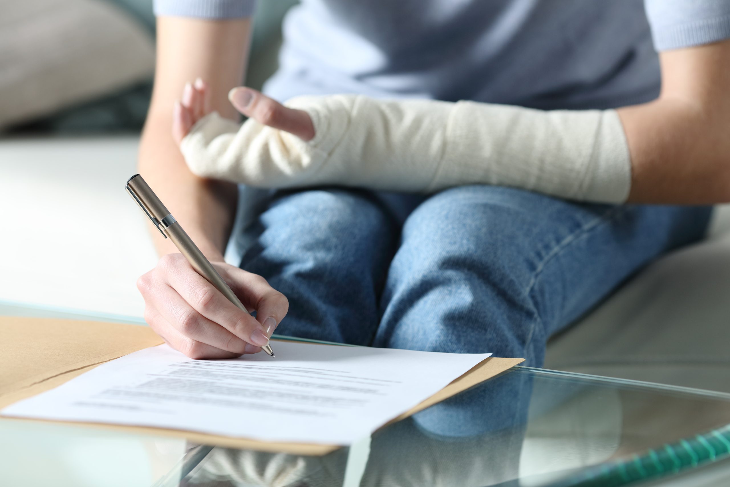 Disabled woman with bandaged arm sigining document